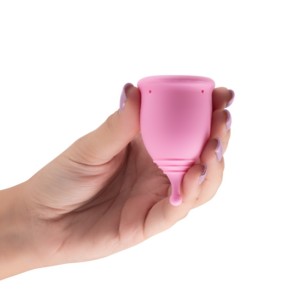 A hand holding the pink menstrual cup to show its size.