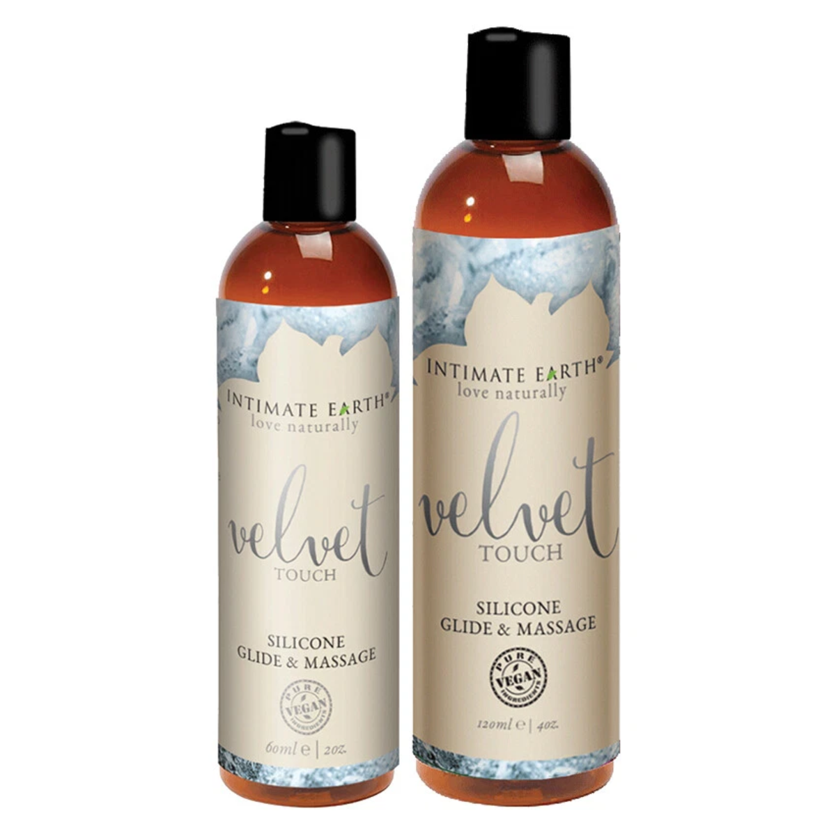 Size comparison view showing two amber bottles of Intimate Earth Velvet Touch silicone glide and massage oil standing side by side in 60 ml (2 fl oz) and 120 ml (4 fl oz) capacities. Main image