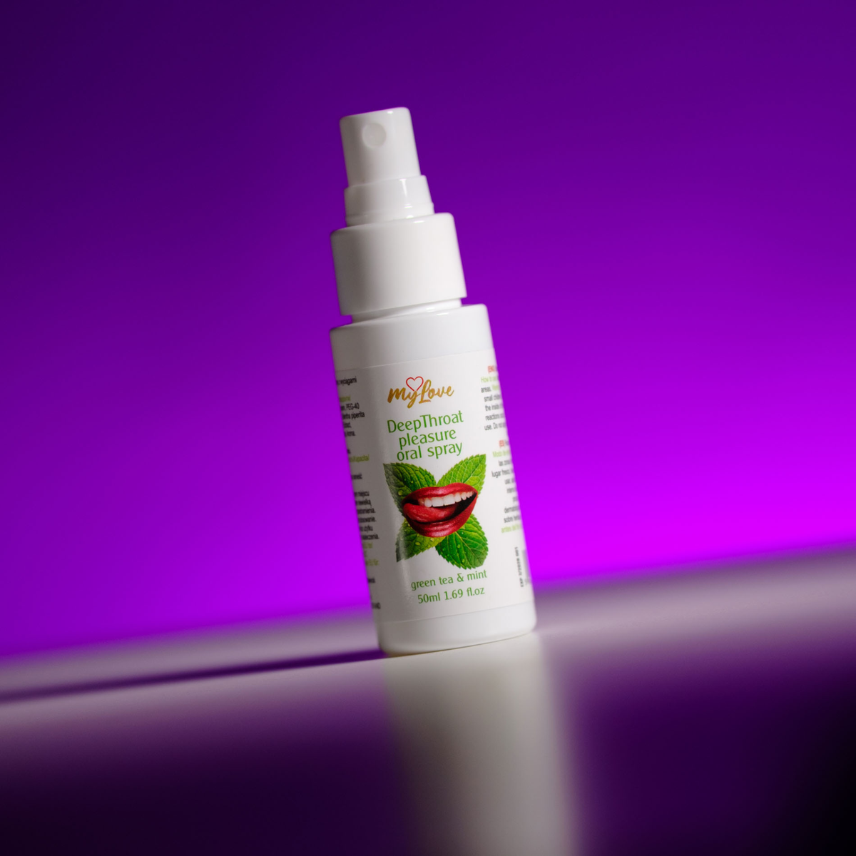 Front view of the 50 ml MyLove Deep Throat Pleasure Oral Spray bottle, angled slightly on a white surface against a vibrant purple backlit background.