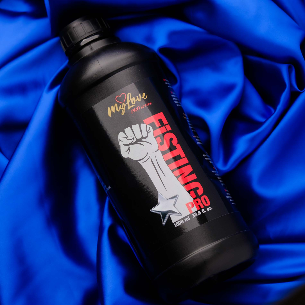 The MyLove Fisting Pro Gel 1000 ml bottle rests at an angle on a rich, draped royal blue satin cloth background.