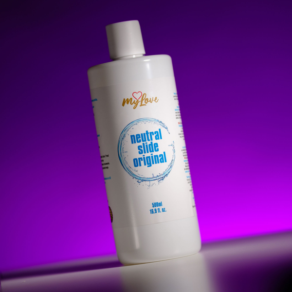 Front view of the 500 ml MyLove Neutral Slide Original bottle standing at an angle on a white surface against a bright purple backlit backdrop.