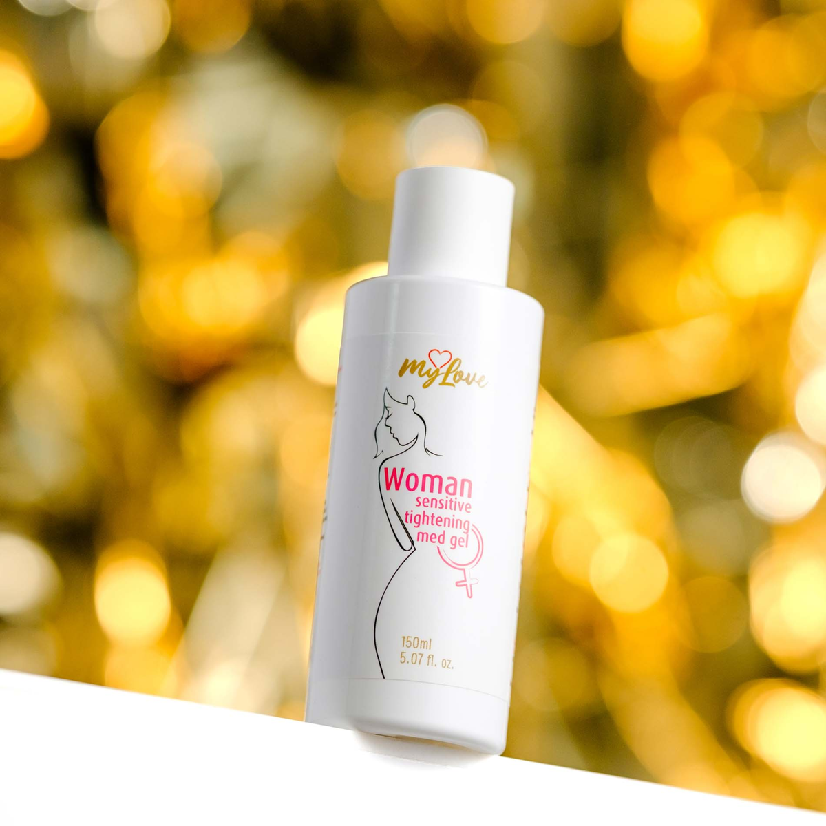 Front view of the 150 ml MyLove Woman Sensitive Tightening Med Gel bottle set against a warm, heavily blurred golden bokeh lighting background.