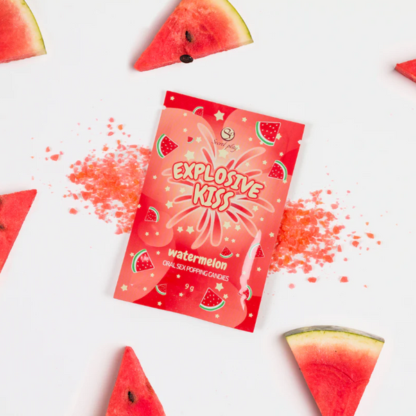 Red packaging of 'Explosive Kiss' watermelon-flavored product with scattered red powder and watermelon bites on a white background.