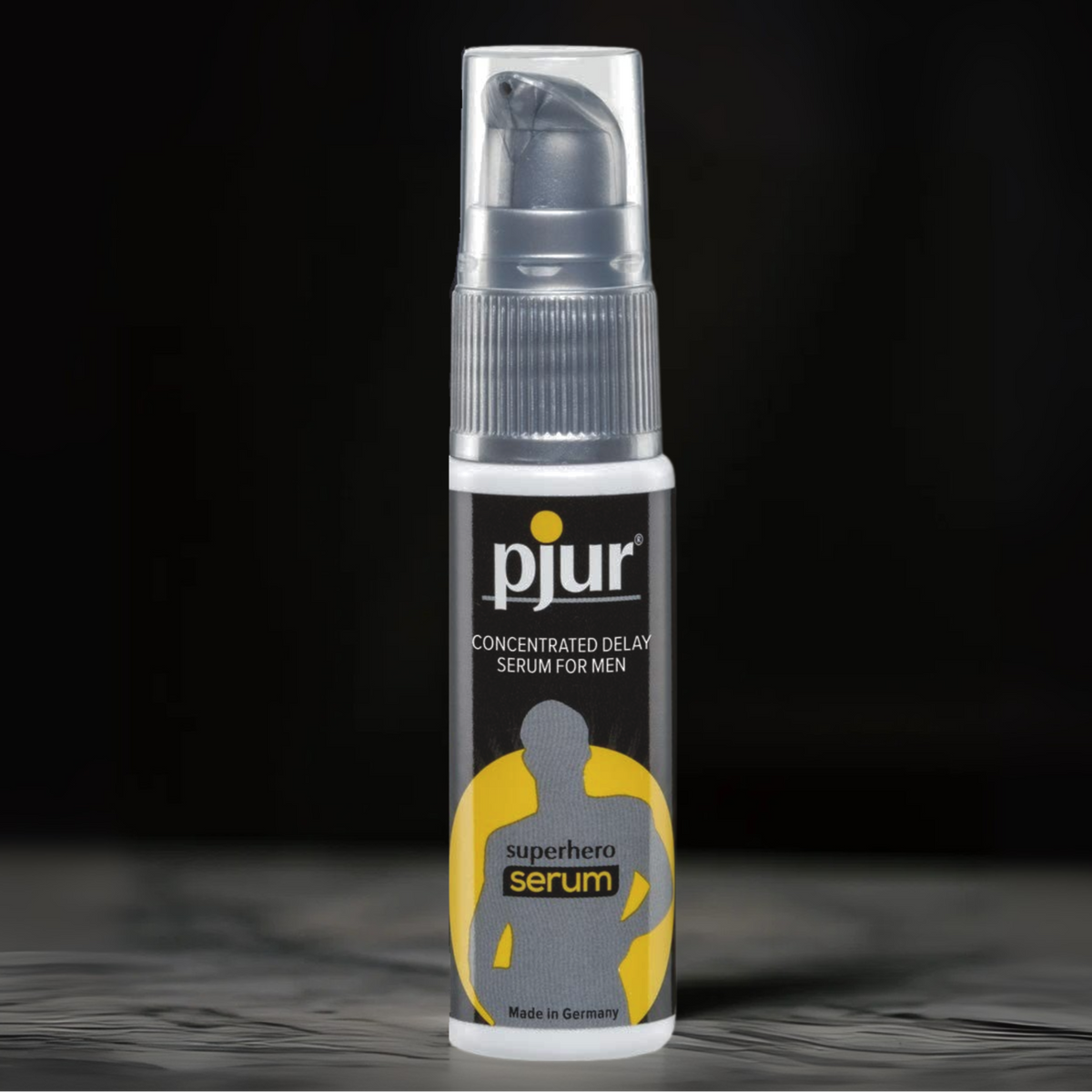 White and black Pjur Superhero Serum bottle with a yellow 'superhero serum' icon, set against a blurred dark background.